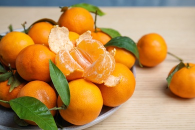 Plate with fresh ripe tangerines on wooden table