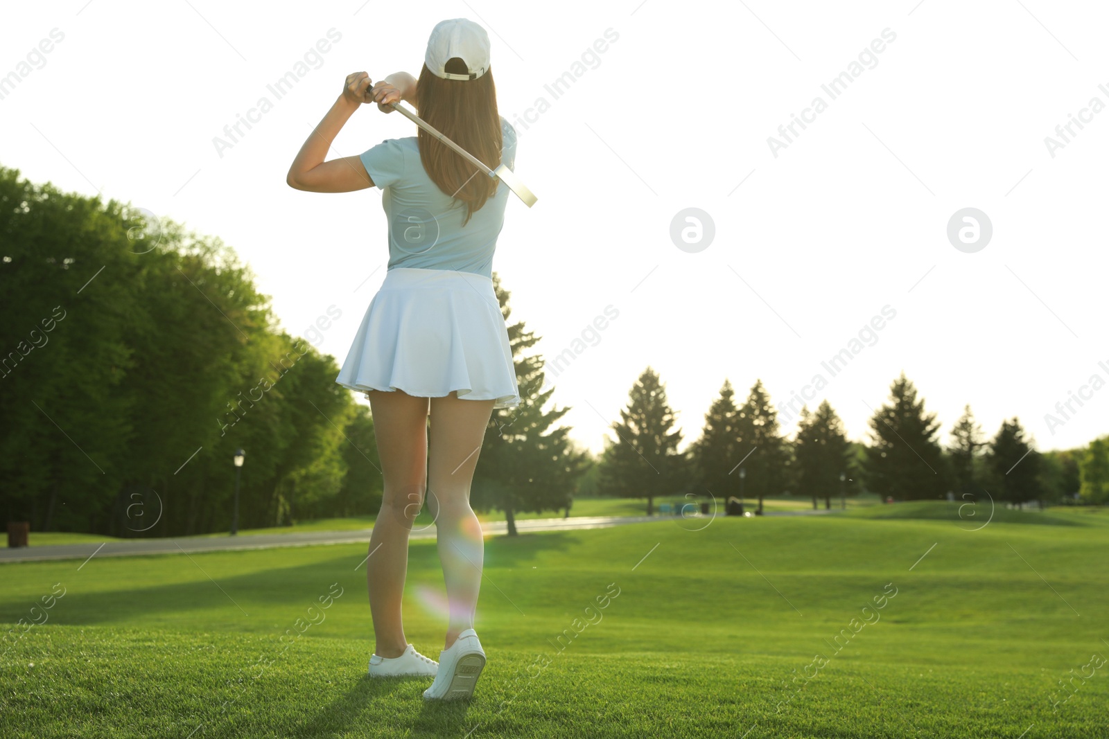 Photo of Woman playing golf on green course, back view. Space for text