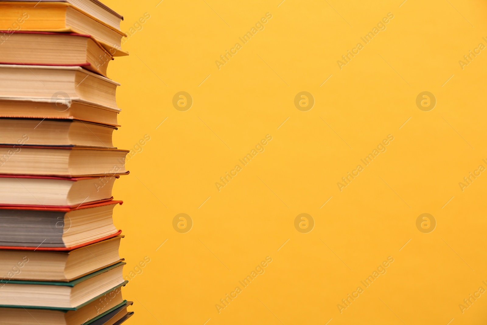 Photo of Many hardcover books on orange background, space for text. Library material