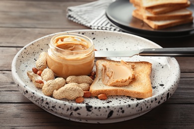 Photo of Jar with creamy peanut butter and toast on plate