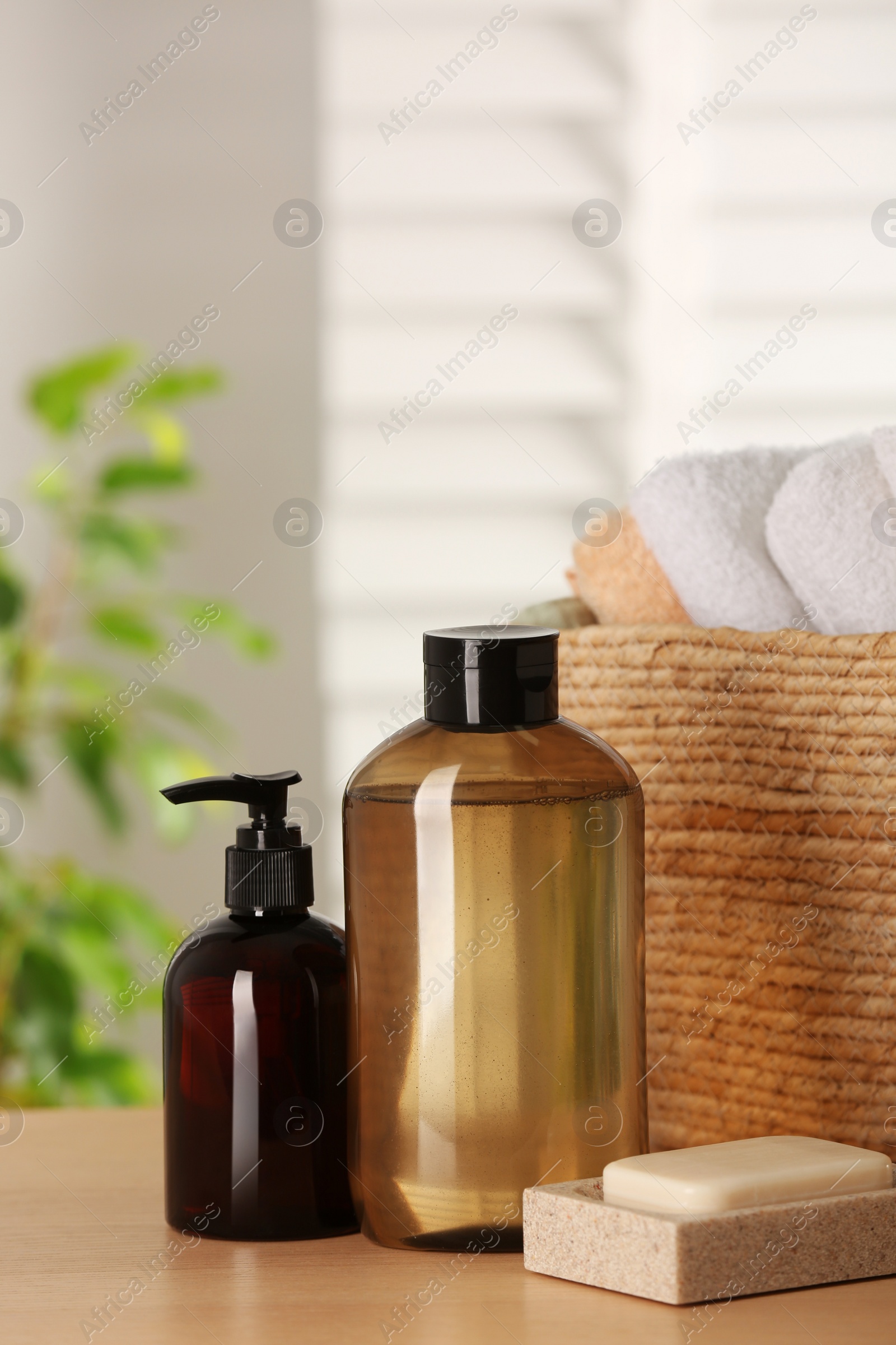 Photo of Solid shampoo bar and bottles of cosmetic product on wooden table in bathroom