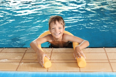 Little boy with swimming noodle in indoor pool