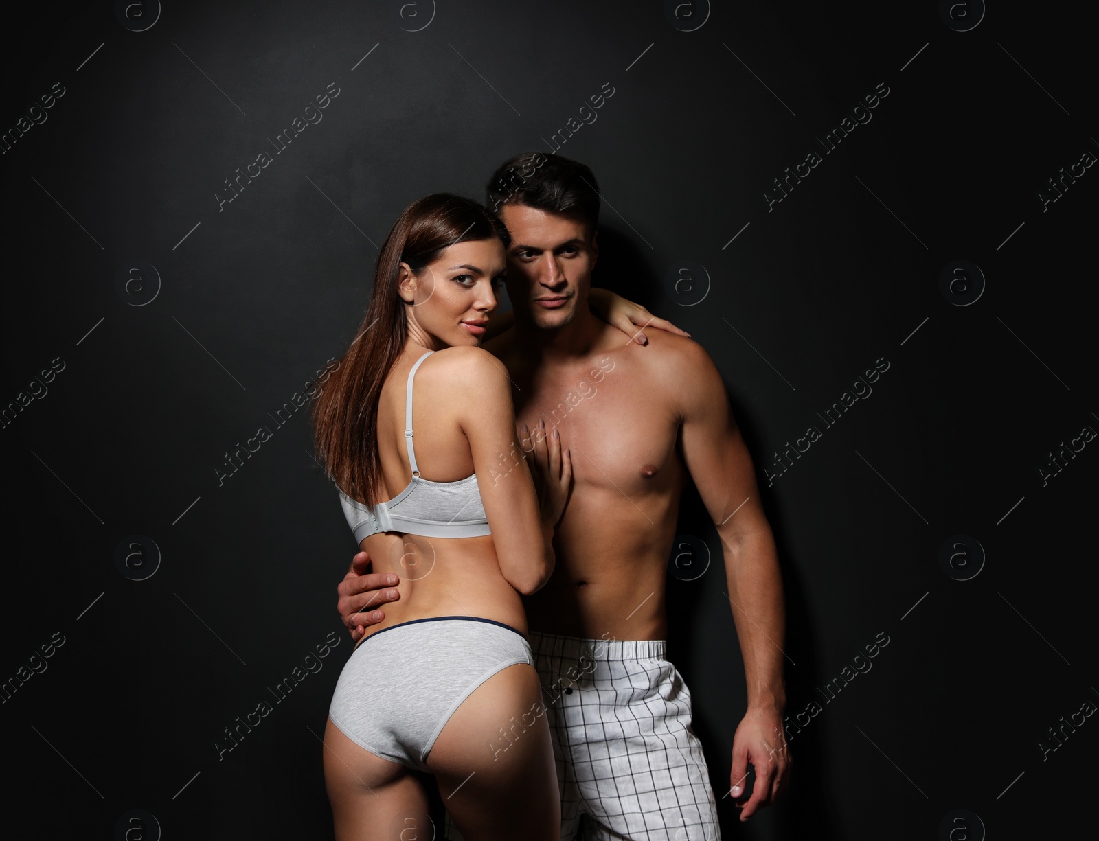 Image of Young couple wearing underwear on black background 