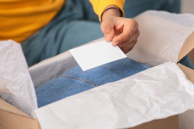 Photo of Young man holding greeting card near parcel with Christmas gift, closeup