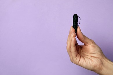 Photo of Woman holding biodegradable dental floss against lilac background, closeup. Space for text
