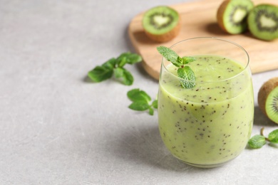 Photo of Delicious kiwi smoothie and fresh ingredients on light grey table, space for text