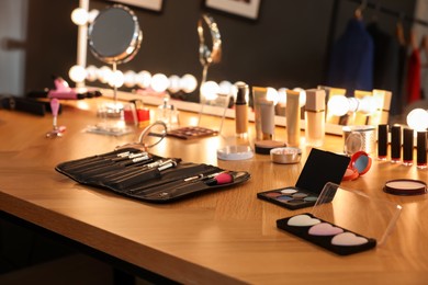 Different makeup products and brushes on wooden table indoors