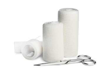 Photo of Medical bandage rolls, sticking plaster and scissors on white background