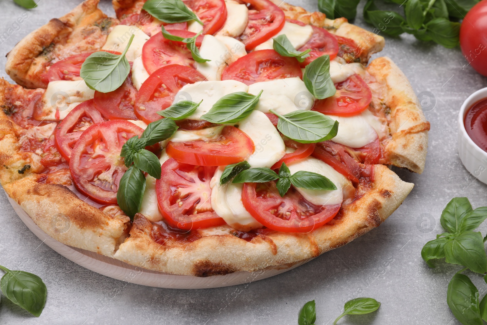 Photo of Delicious Caprese pizza with tomatoes, mozzarella and basil on light grey table, closeup