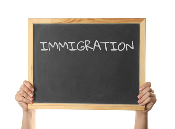 Woman holding blackboard with word IMMIGRATION on white background, closeup