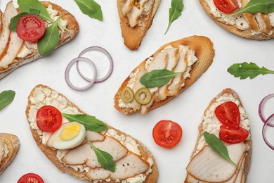 Photo of Different delicious chicken bruschettas on white table, flat lay