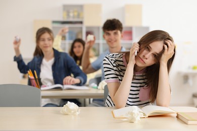 Photo of Teen problems. Students bullying their classmate in classroom, selective focus