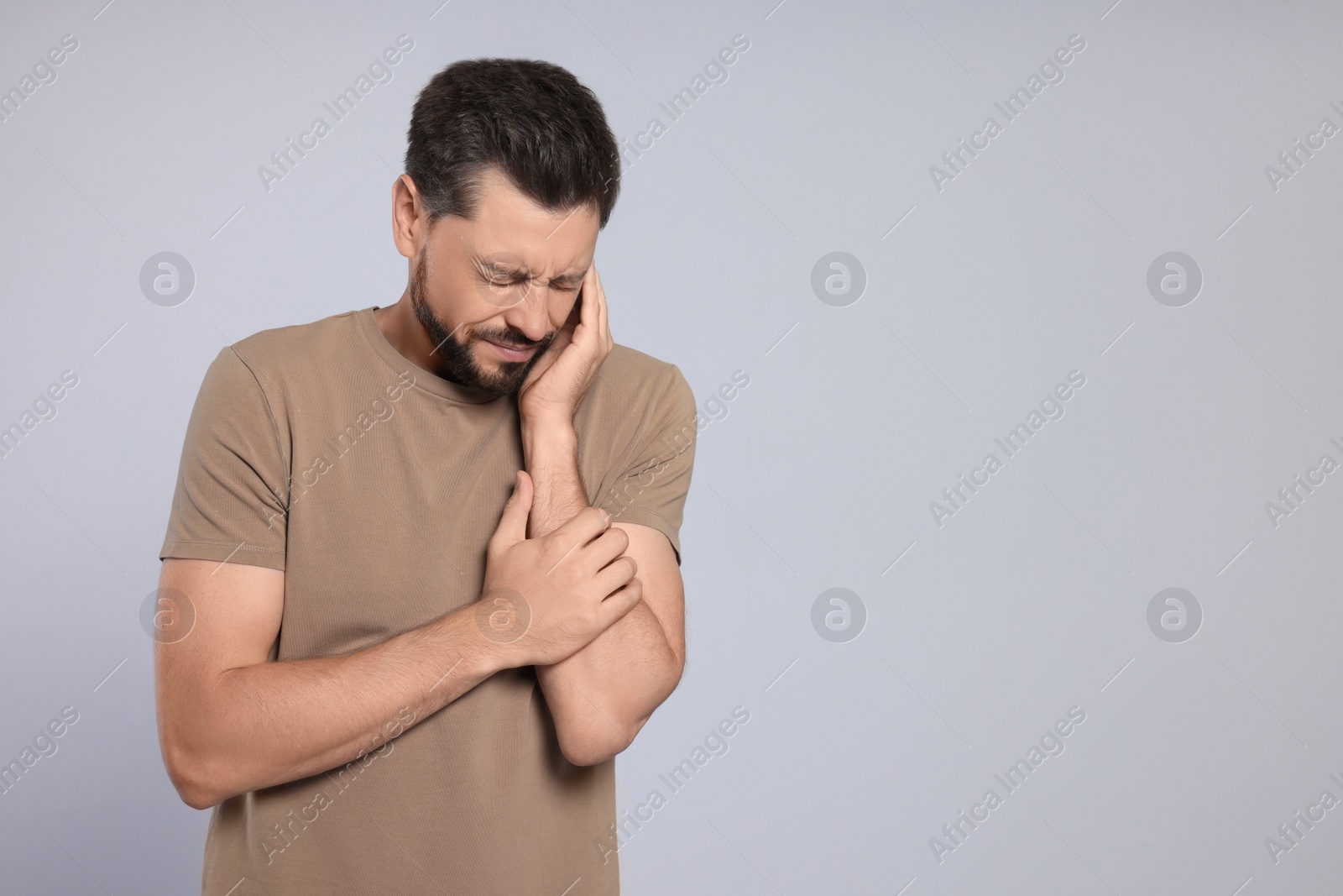 Photo of Man suffering from ear pain on grey background, space for text