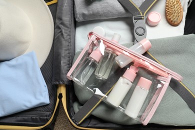 Photo of Plastic bag of cosmetic travel kit in suitcase, top view