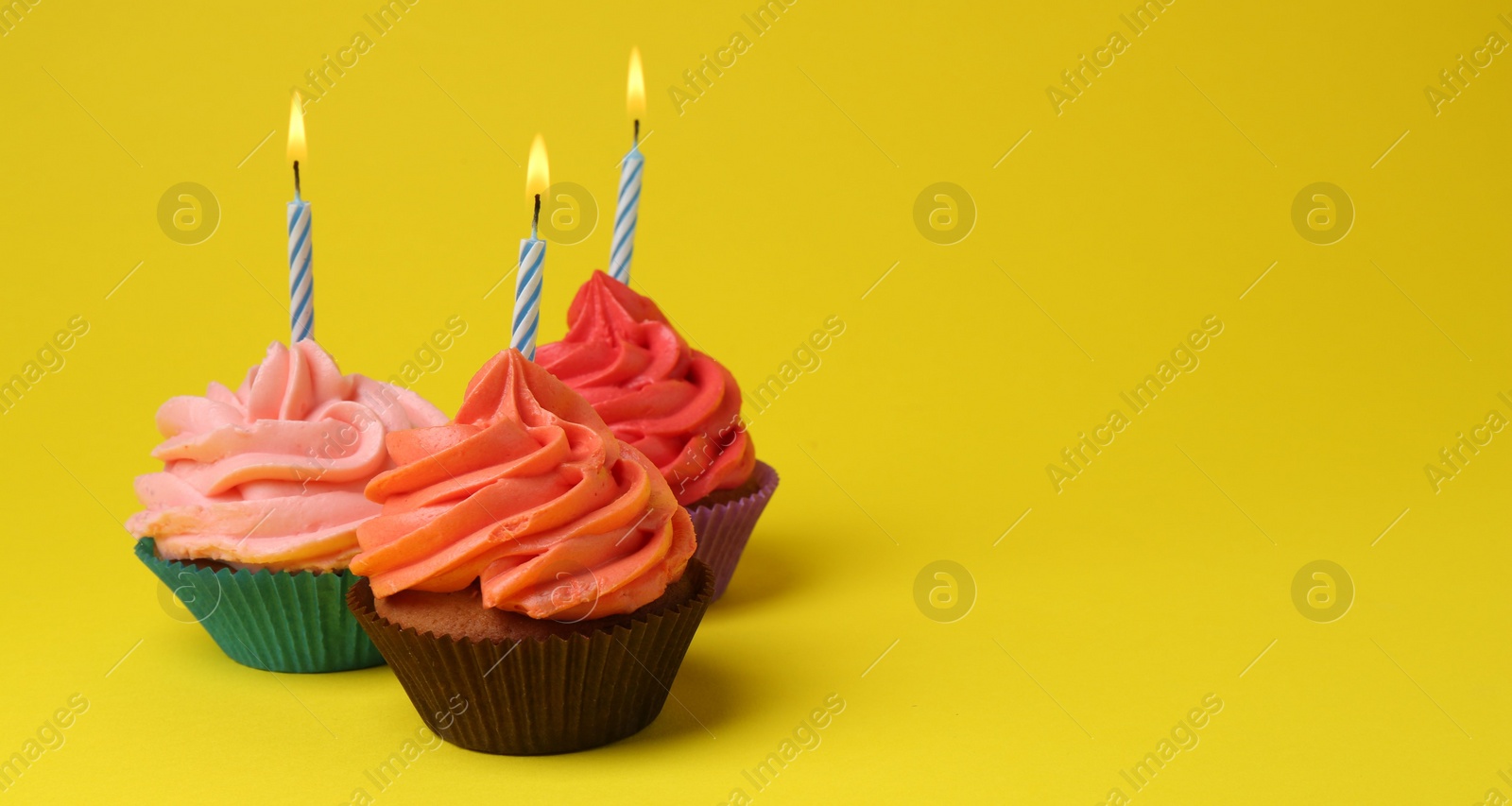 Photo of Delicious birthday cupcakes with bright cream on yellow background. Banner design and space for text