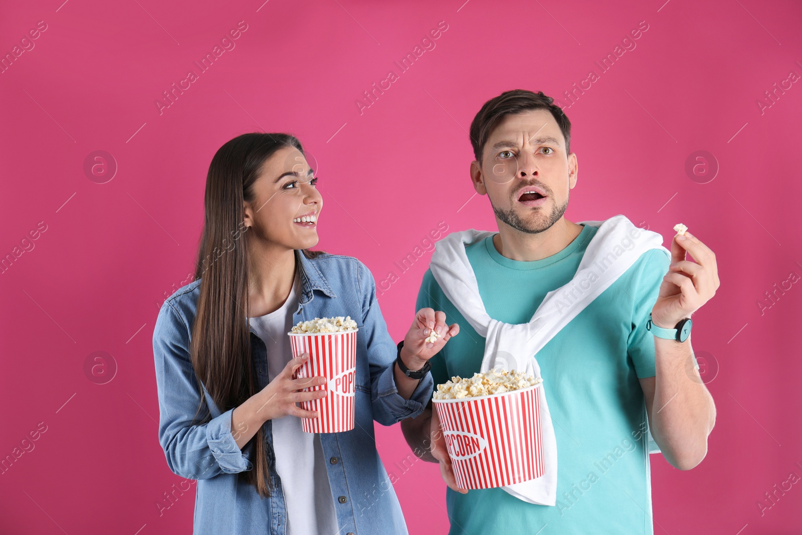 Photo of Emotional couple with tasty popcorn on color background