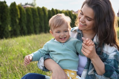 Happy mother with her cute baby at backyard on sunny day, space for text