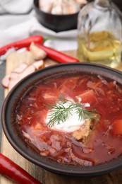 Photo of Tasty borscht with sour cream in bowl on table, closeup