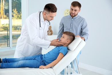 Photo of Father and son visiting pediatrician. Doctor working with patient in hospital