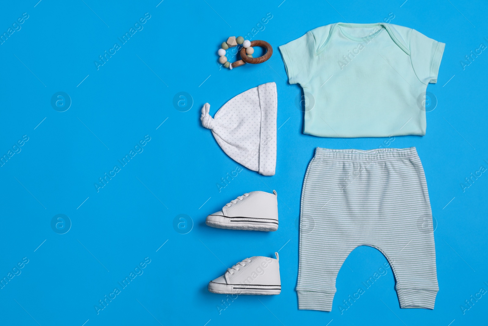 Photo of Flat lay composition with baby clothes and toy on blue background. Space for text