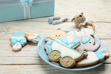 Photo of Plate of baby shower cookies and accessories on white wooden table