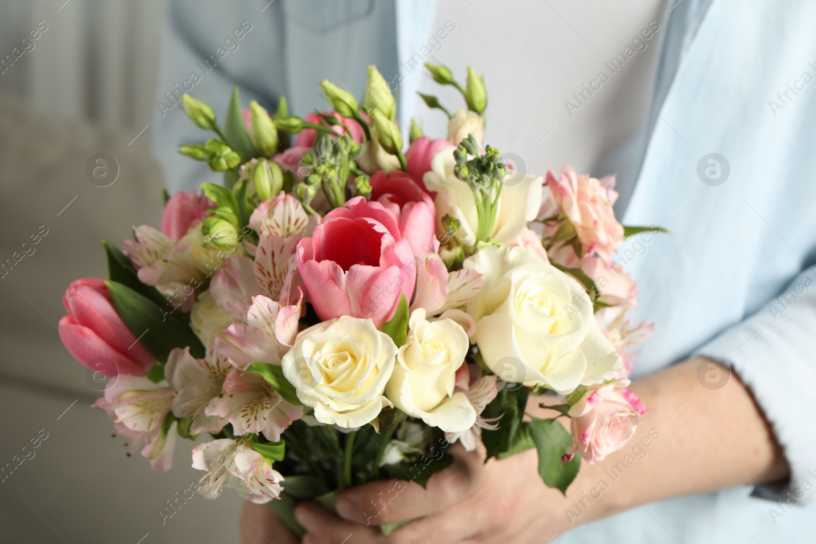 Photo of Man holding bouquet of beautiful flowers indoors, closeup