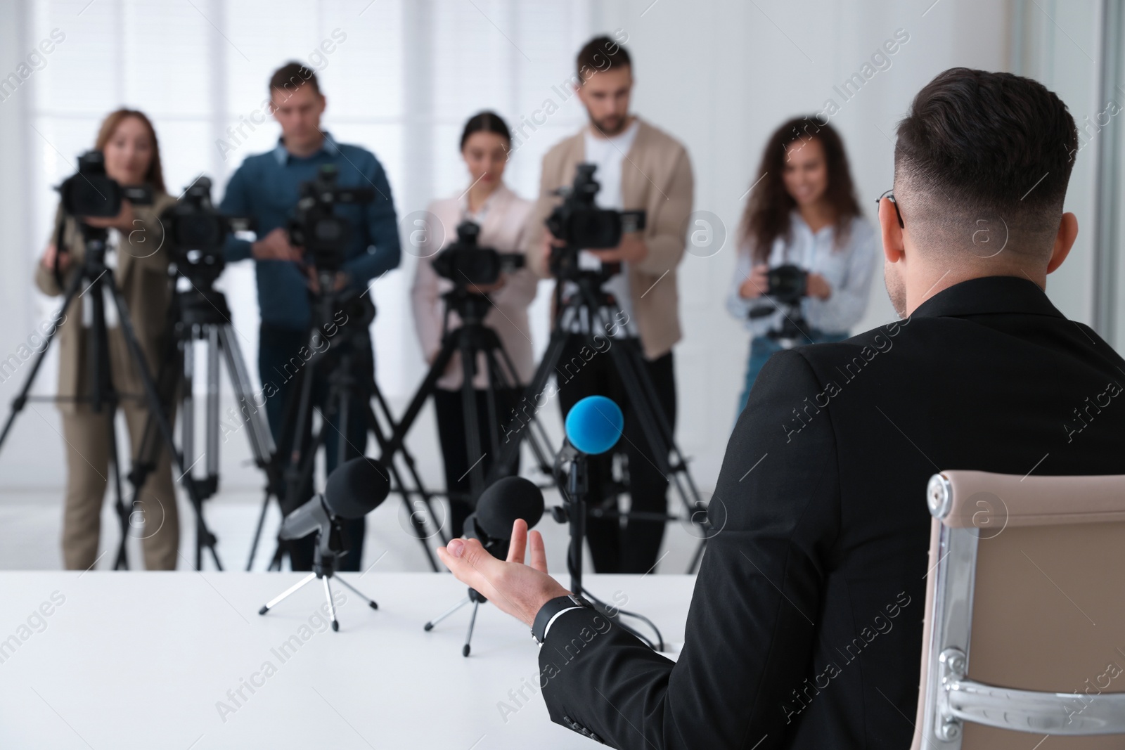 Photo of Businessman giving interview to journalists at official event, back view