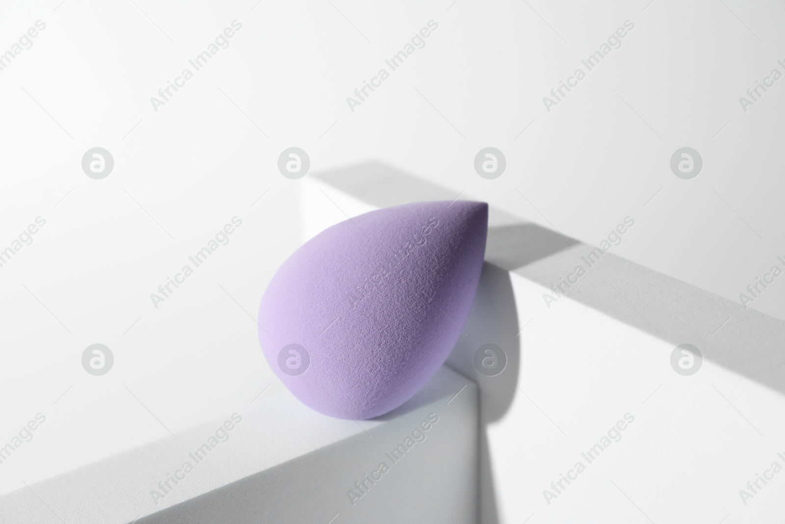 Photo of Stylish presentation of violet makeup sponge on white background