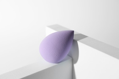 Photo of Stylish presentation of violet makeup sponge on white background