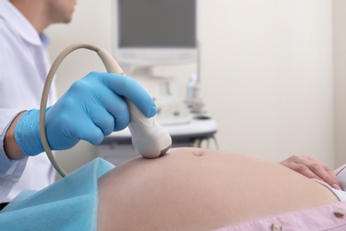 Photo of Pregnant woman undergoing ultrasound scan in clinic, closeup