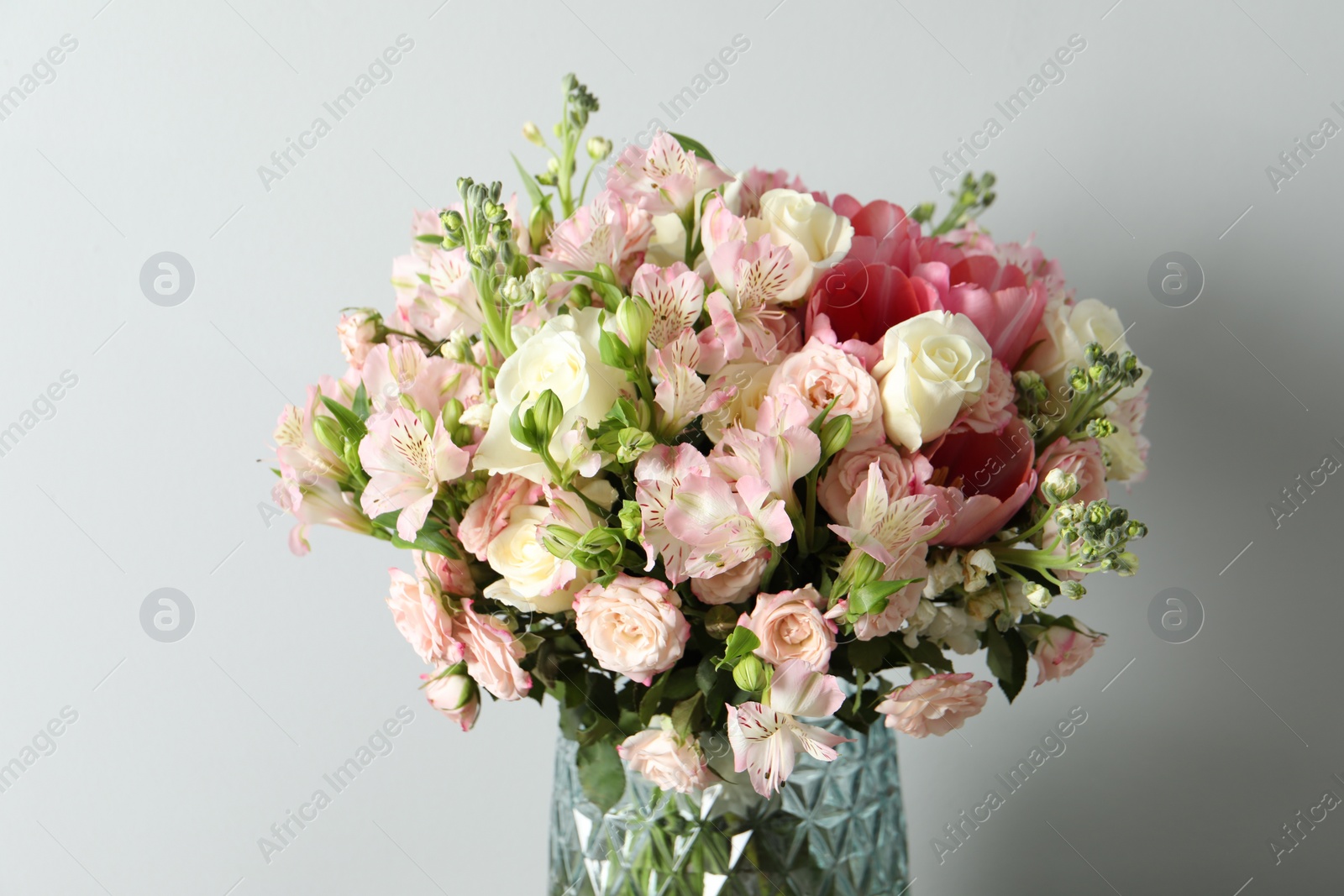 Photo of Beautiful bouquet of fresh flowers in vase on light background