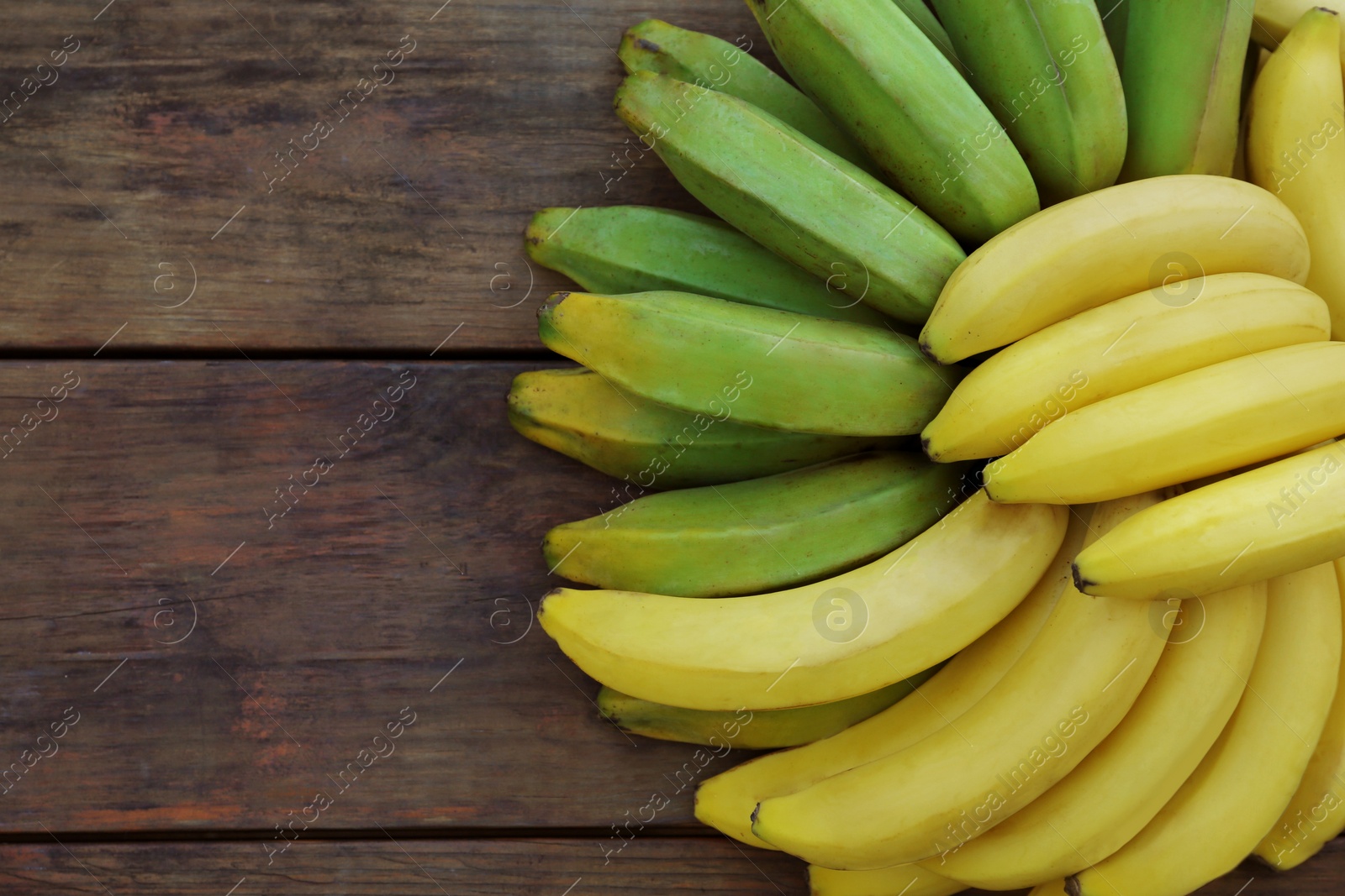 Photo of Bunches of tasty bananas on wooden table, flat lay. Space for text