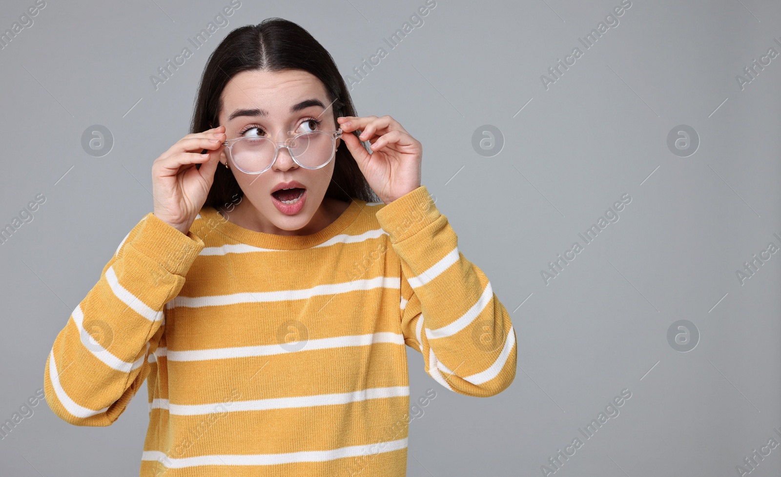 Photo of Portrait of surprised woman on grey background. Space for text