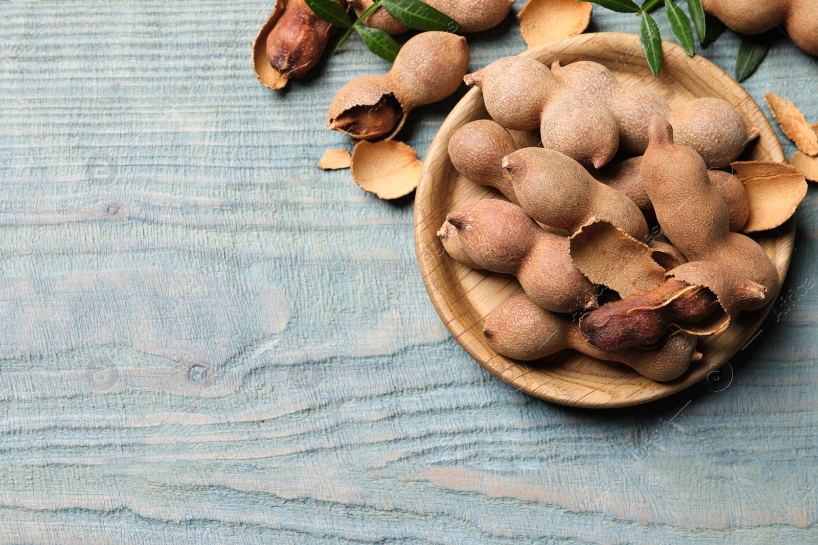 Photo of Delicious ripe tamarinds on blue wooden table, flat lay. Space for text