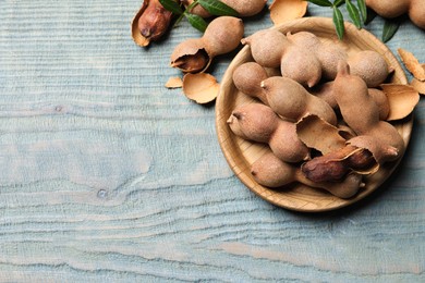 Photo of Delicious ripe tamarinds on blue wooden table, flat lay. Space for text