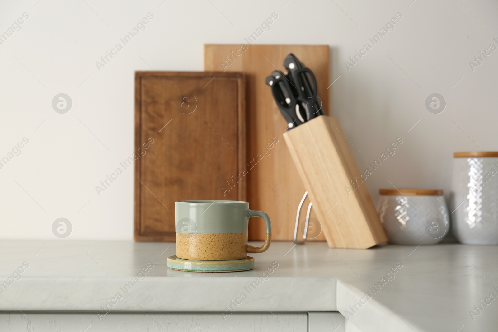 Photo of One ceramic mug with coaster on light countertop in kitchen