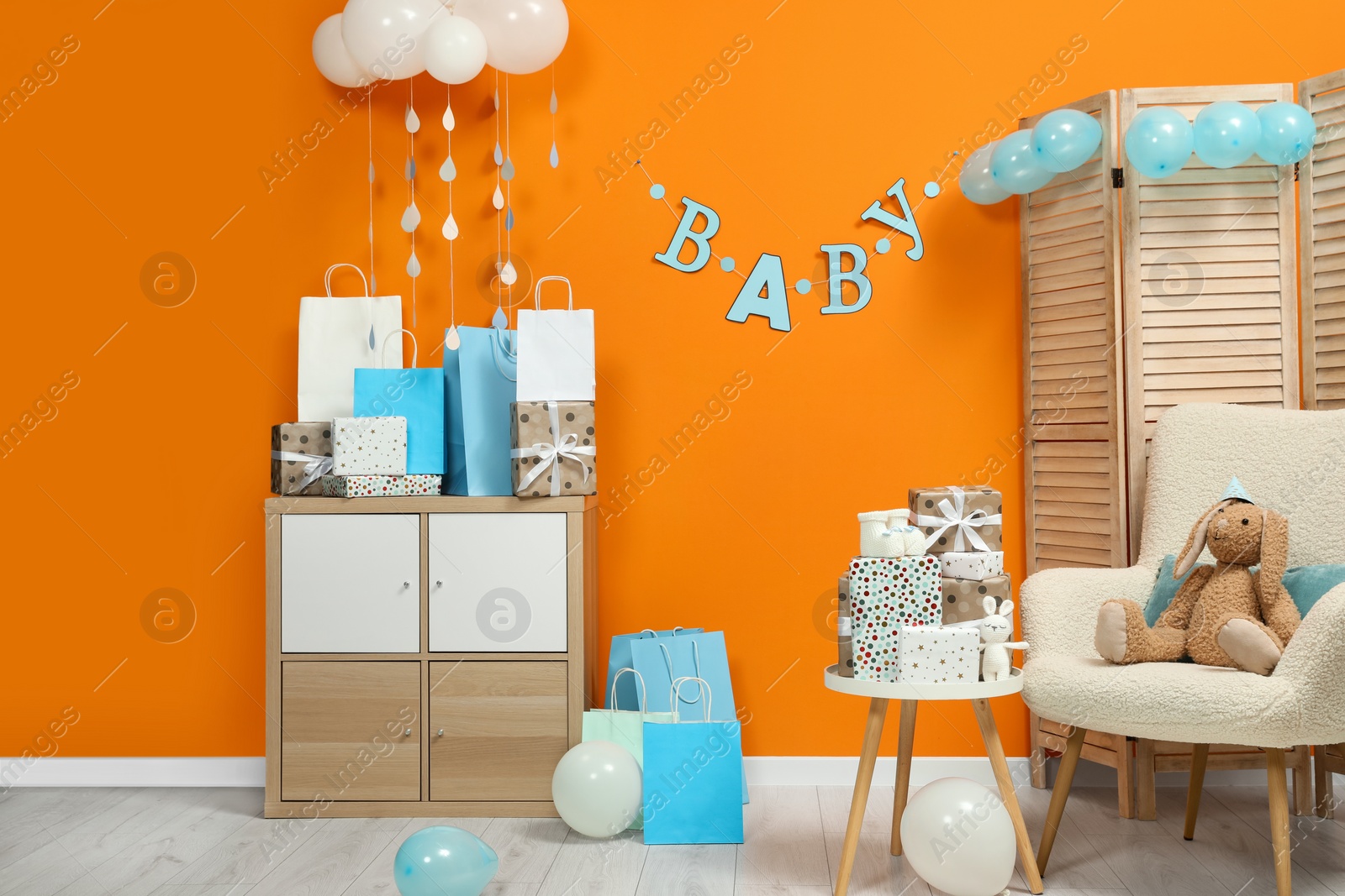 Photo of Baby shower party. Festive decor, booties, toys and gift boxes in stylish room