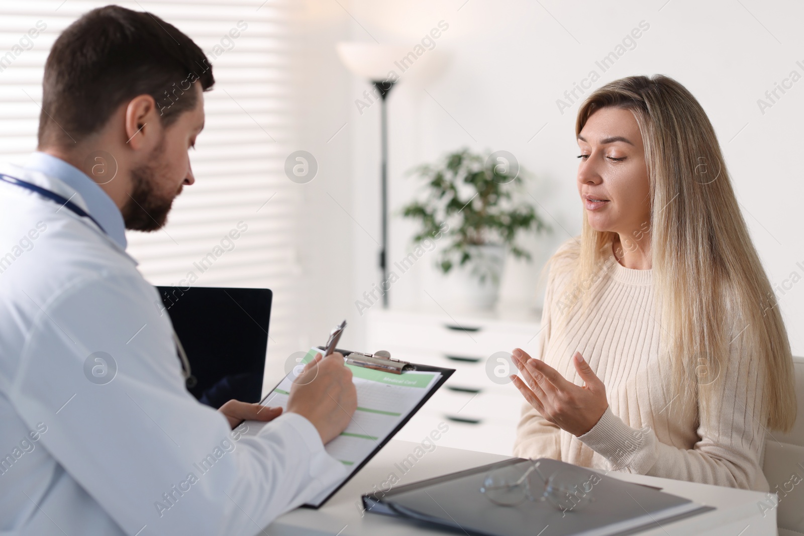 Photo of Professional doctor working with patient at white table in hospital