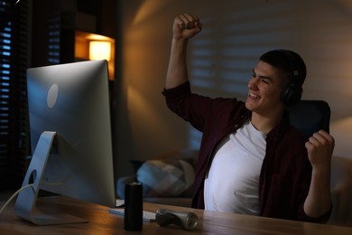 Photo of Emotional man playing video games on computer at table indoors