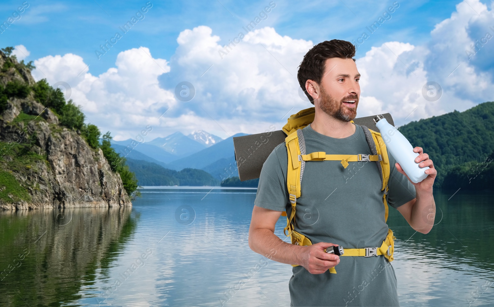 Image of Happy tourist with yellow backpack near lake