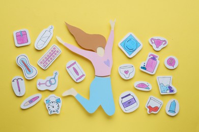 Woman`s health. Paper female figure and different stickers on yellow background, flat lay
