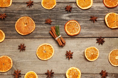 Photo of Flat lay composition with dry orange slices, anise stars and cinnamon sticks on wooden table
