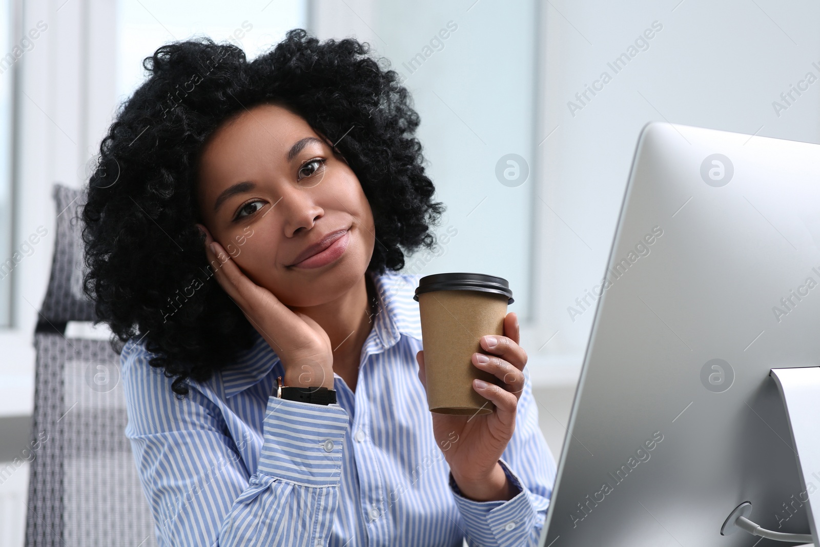 Photo of Young woman with cup of drink working on computer in office