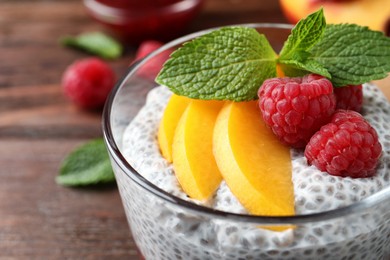 Photo of Delicious chia pudding with raspberries, peach and mint in glass, closeup