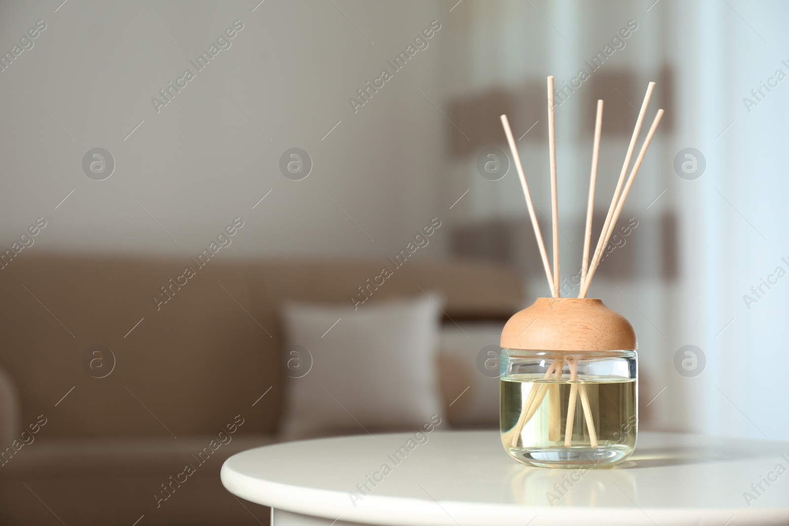 Photo of Aromatic reed air freshener on table indoors. Space for text