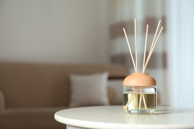 Photo of Aromatic reed air freshener on table indoors. Space for text