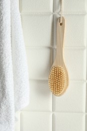 Photo of Bath accessories. Bamboo brush and terry towel on white tiled wall