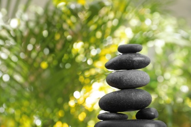 Stack of stones and blurred green leaves on background, space for text. Zen concept