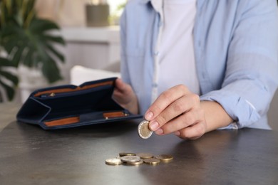 Poor woman counting coins at grey table indoors, closeup