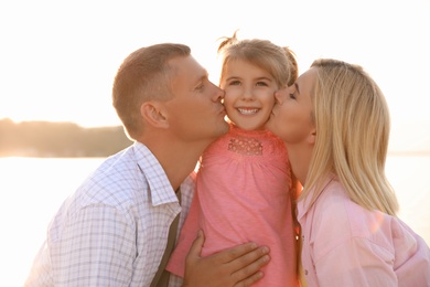 Photo of Happy parents with their child on beach. Spending time in nature